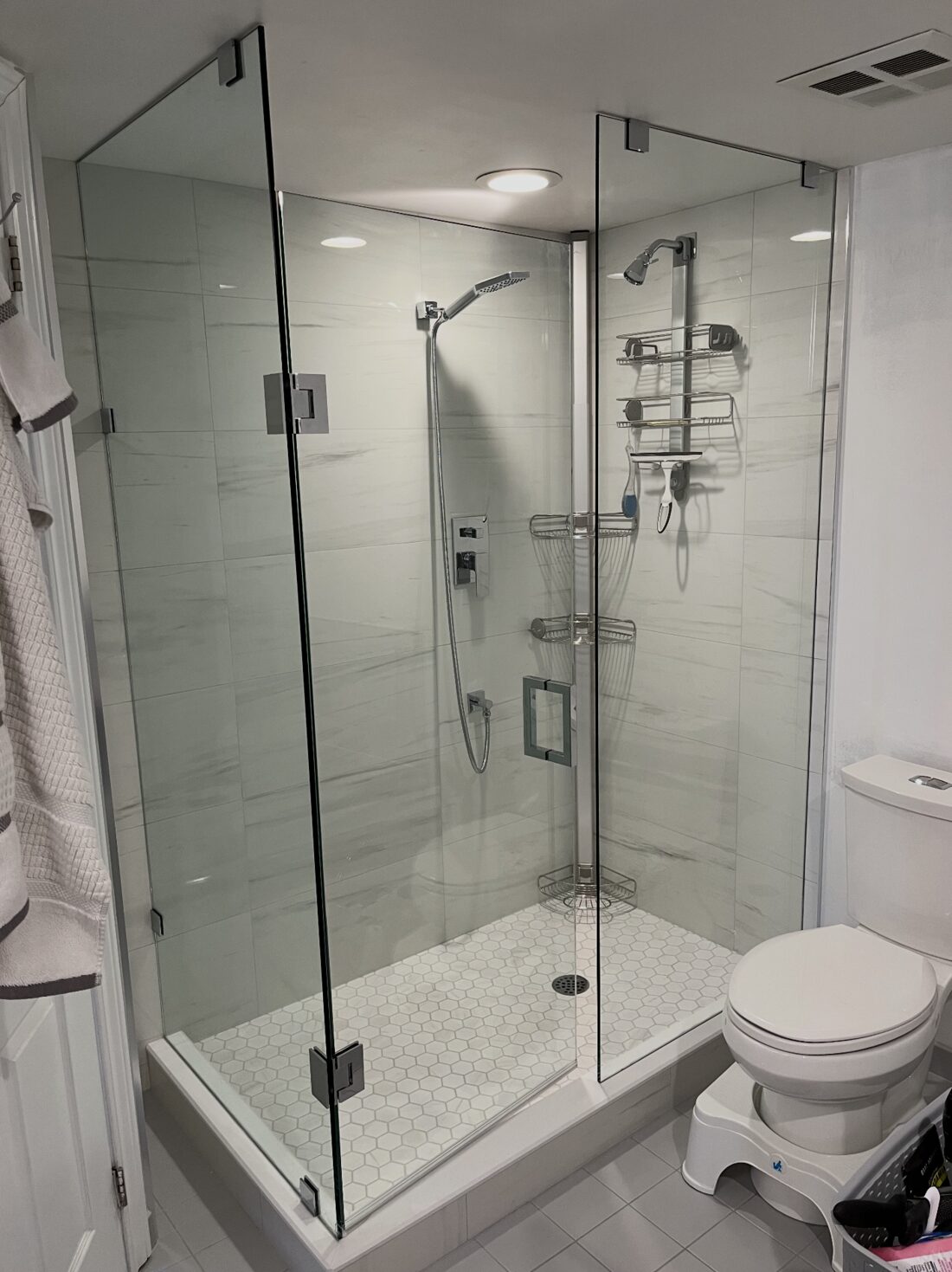 Corner glass shower with marble-look tile and rain head — Reno-eX condo bathroom renovation