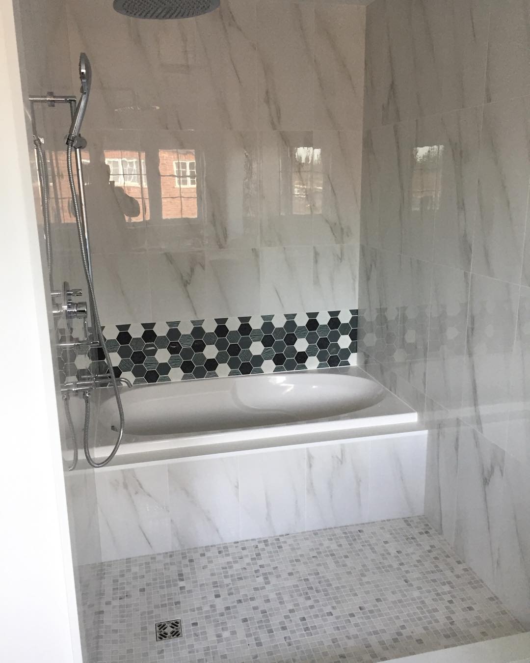 Tub and rain shower in marble surround with mosaic floor, 2020