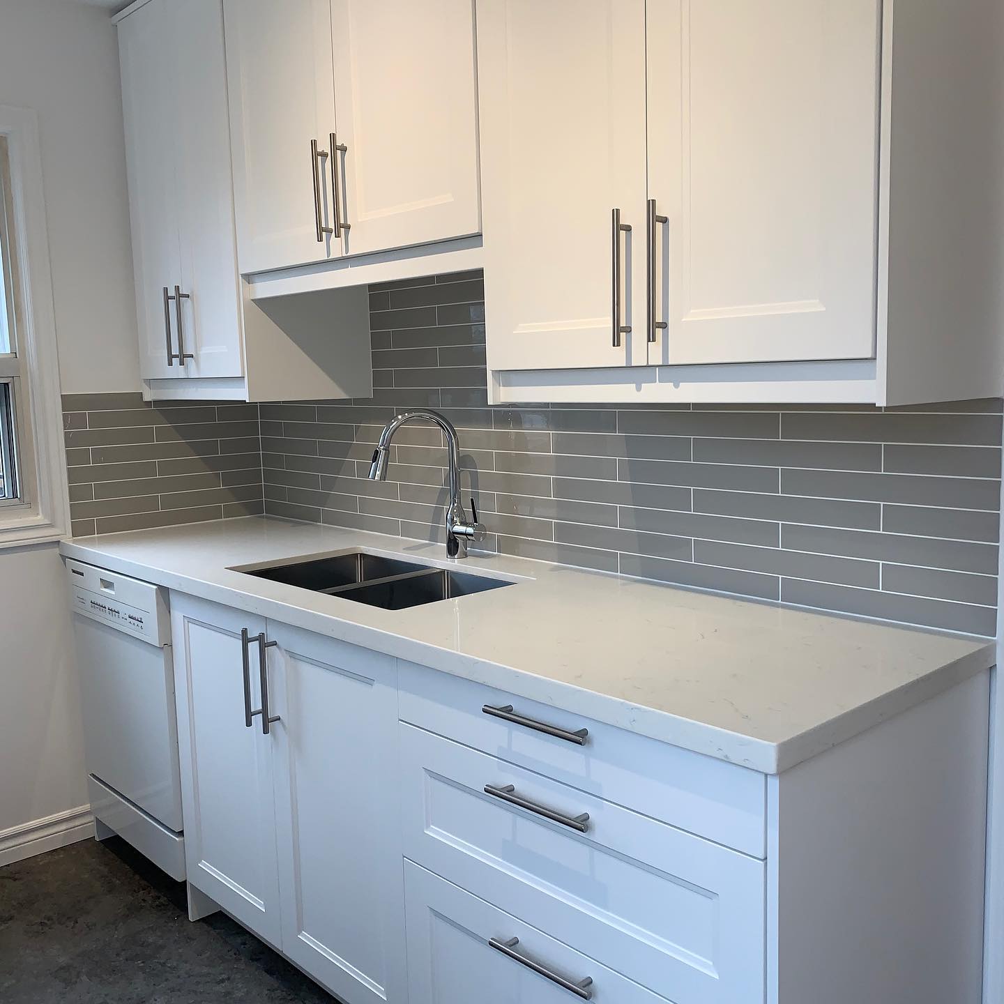 Same kitchen after Reno-eX renovation — white shaker cabinets, quartz counters, grey glass subway tile
